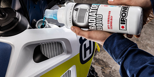 Man pouring radiator liquid into the radiator of the motorcycle.