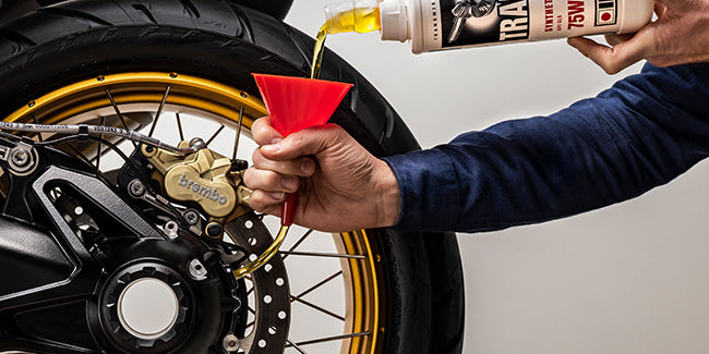 Man pouring Trans 4 80w90 GL5 transmission oil into his motorcycle.